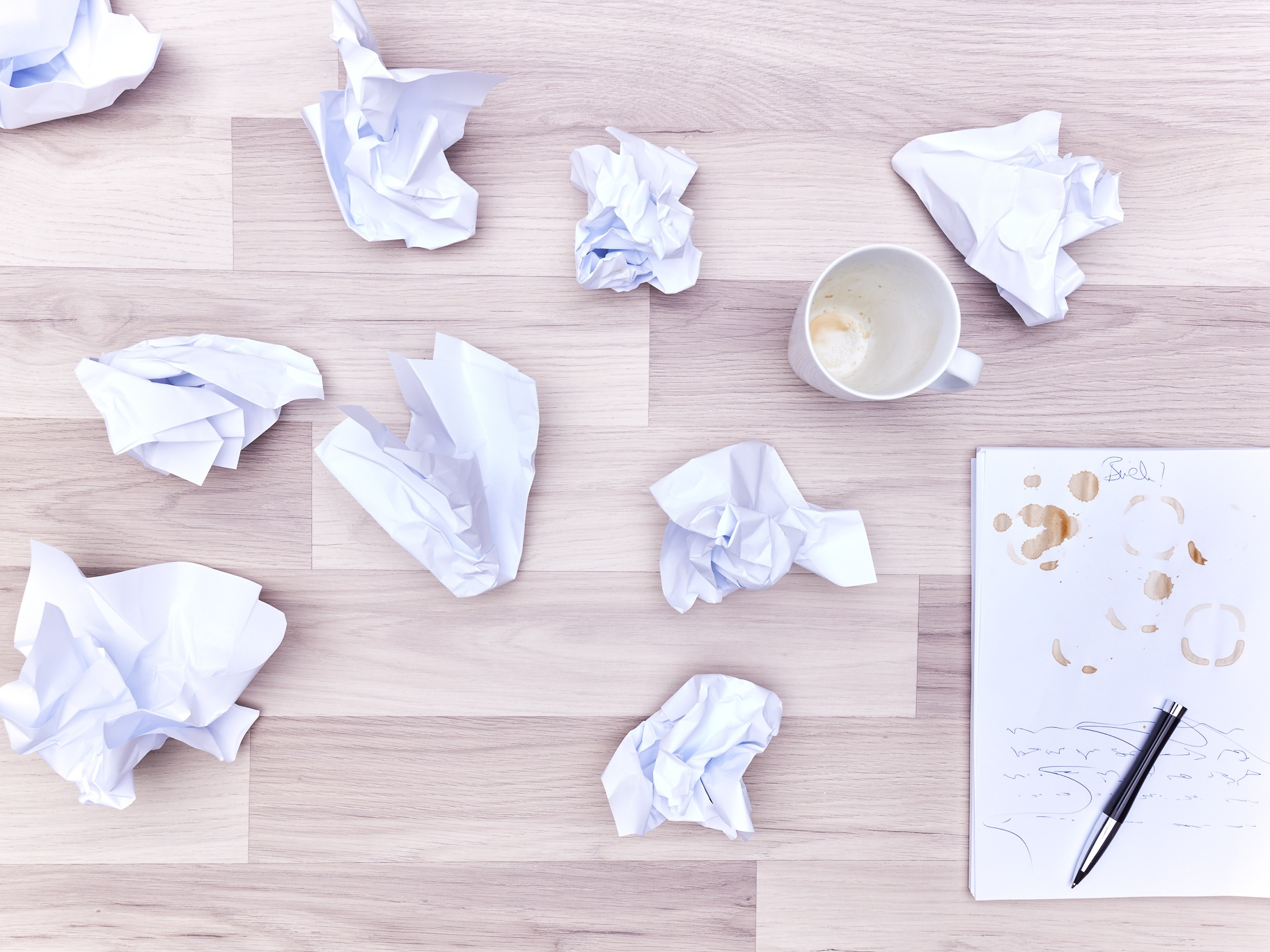 zusammengeknülltes Papier neben leerem Schreibblock