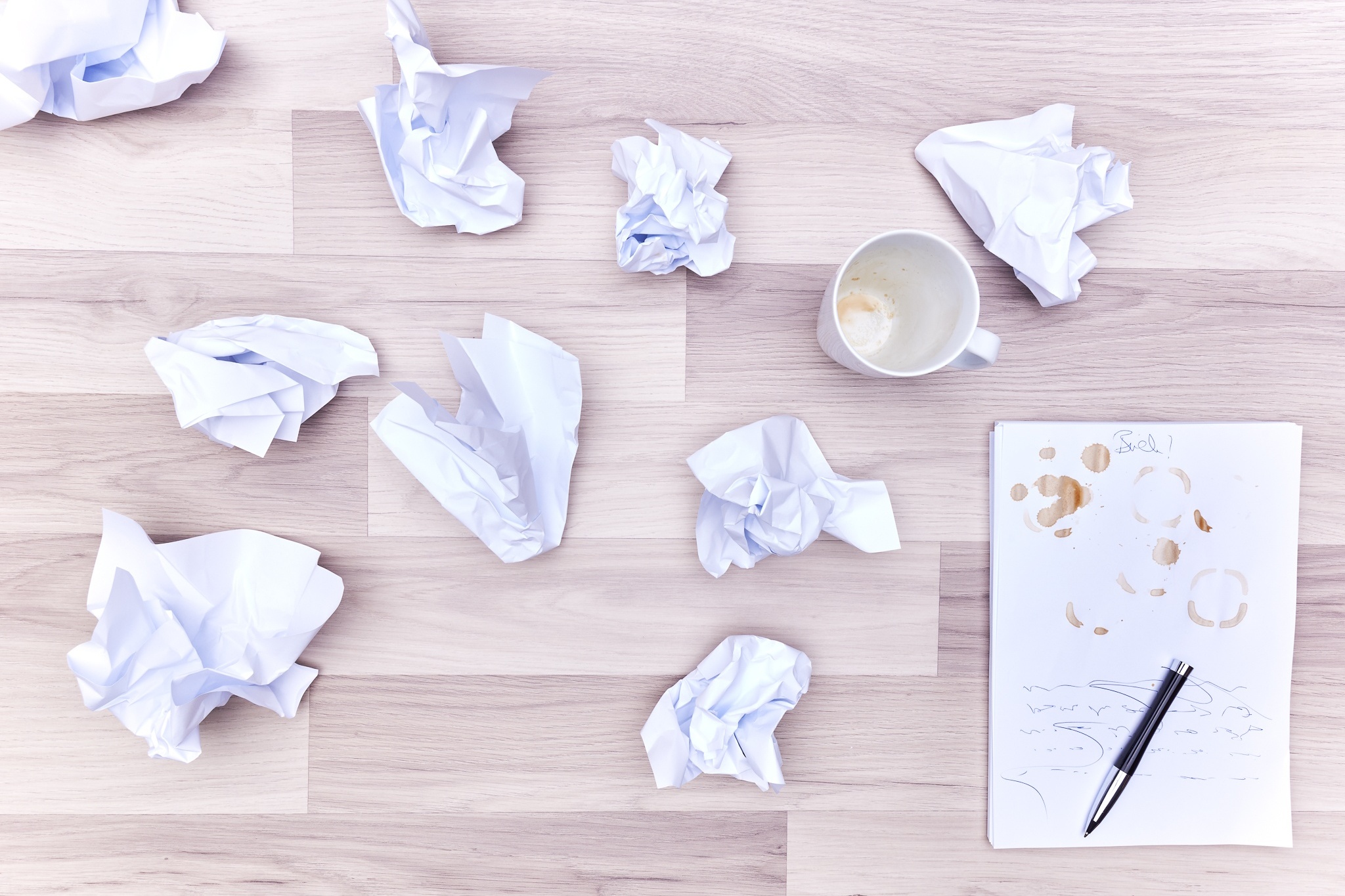 zusammengeknülltes Papier neben leerem Schreibblock