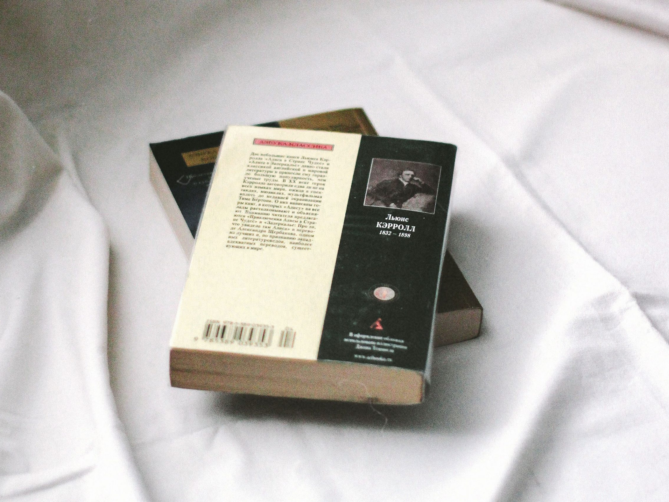 Bücher auf weißem Laken, wobei bei dem oberen Buch die Rückseite lesbar ist